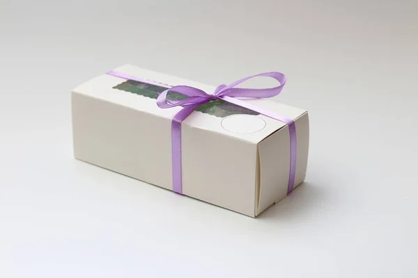Caixa de papelão branco com um top transparente amarrado com uma fita lilás isolada em um fundo branco. Um presente maravilhoso para o Dia dos Namorados, aniversário . — Fotografia de Stock