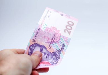 Beyaz arka planda bir erkeğin elinde 200 Hryvnia banknotu. Ukrayna 'da rüşvet vermek. Avrupa para değişimi. Ukrayna para birimi