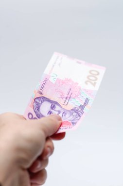 Beyaz arka planda bir erkeğin elinde 200 Hryvnia banknotu. Ukrayna 'da rüşvet vermek. Avrupa para değişimi. Ukrayna para birimi