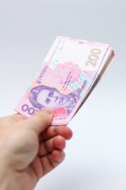 Beyaz arka planda bir erkeğin elinde 200 Hryvnia banknotu. Ukrayna 'da rüşvet vermek. Avrupa para değişimi. Ukrayna para birimi