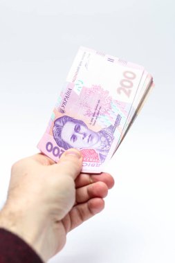 Beyaz arka planda bir erkeğin elinde 200 Hryvnia banknotu. Ukrayna 'da rüşvet vermek. Avrupa para değişimi. Ukrayna para birimi