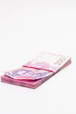 200 Ukrayna Hrivniası 'na ait banknotlarda bir sürü yeni banknot ve gölgeli beyaz bir arka planda izole edilmiş elastik bant var. Avrupa para değişimi. Ukrayna parası. Seçici odak