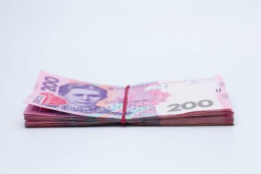 200 Ukrayna Hrivniası 'na ait banknotlarda bir sürü yeni banknot ve gölgeli beyaz bir arka planda izole edilmiş elastik bant var. Avrupa para değişimi. Ukrayna parası. Seçici odak