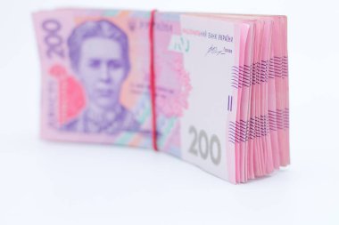 200 Ukrayna Hrivniası 'na ait banknotlarda bir sürü yeni banknot ve gölgeli beyaz bir arka planda izole edilmiş elastik bant var. Avrupa para değişimi. Ukrayna parası. Seçici odak