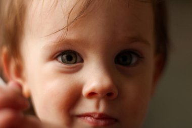 Yumuşak ışık ve bulanık arka planda kirli bir yüzü olan küçük, beyaz bir bebeğin yakın plan portresi.