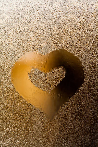 Water droplets with love heart shape on transparent glass. Golden abstract frame and liquid textured bubbles pattern. macro view. Shallow depth of field. Valentines day concept. Vertical