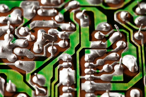 Retro style hardware technology concept with green circuit board. Macro view electronic chip soldering paths and trace. Selective focus photo