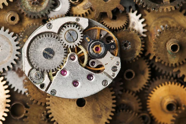 Vintage clock mechanism close-up. Aged hand watches parts on bronze gears background