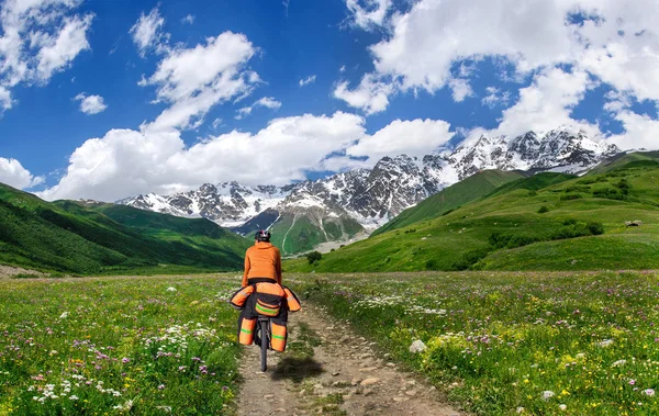 Cyclist with large backpack rides on dirt road against beautiful sky — Stock Photo, Image