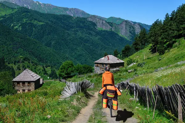Cyclist with large backpack rides on mountain village in Georgia — Stock Photo, Image