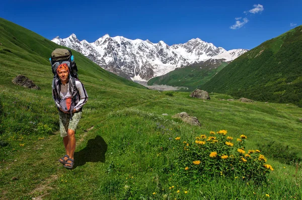 Turista con un grande zaino viaggia nelle montagne del Caucaso, Georgia . — Foto Stock