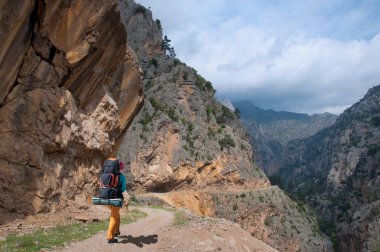 Turizm büyük bir sırt çantası ile dağlarda kanyonda yol gider