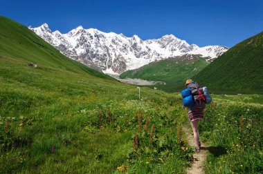 Lardaard buz sonbaharda Georgia Svaneti manzaralı dağ izinde turist büyük sırt çantası ile yükselir