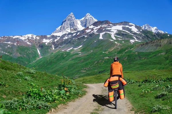 Un hombre en bicicleta con una gran mochila monta en un camino de montaña Georgia — Foto de Stock