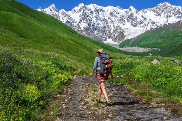 Tourist with large backpack rises on mountain trail with view of the Lardaard ice-fall in Georgia Svaneti — Stock Photo, Image