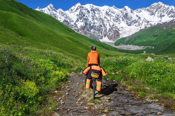 A man on bicycle with a large backpack rides on a mountain road Georgia — Stock Photo, Image