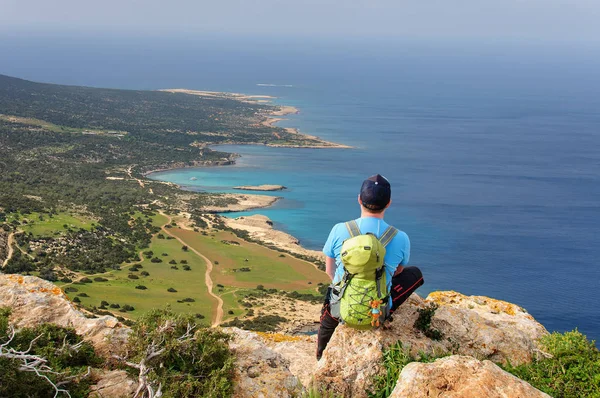 Man with backpack sitting on a rock and looking at the Mediterranean Sea Royalty Free Stock Photos
