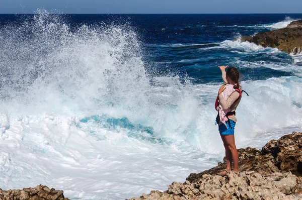 Mujer joven con niño se para en el precipicio de piedra y mira una tormenta en el mar Mediterráneo —  Fotos de Stock