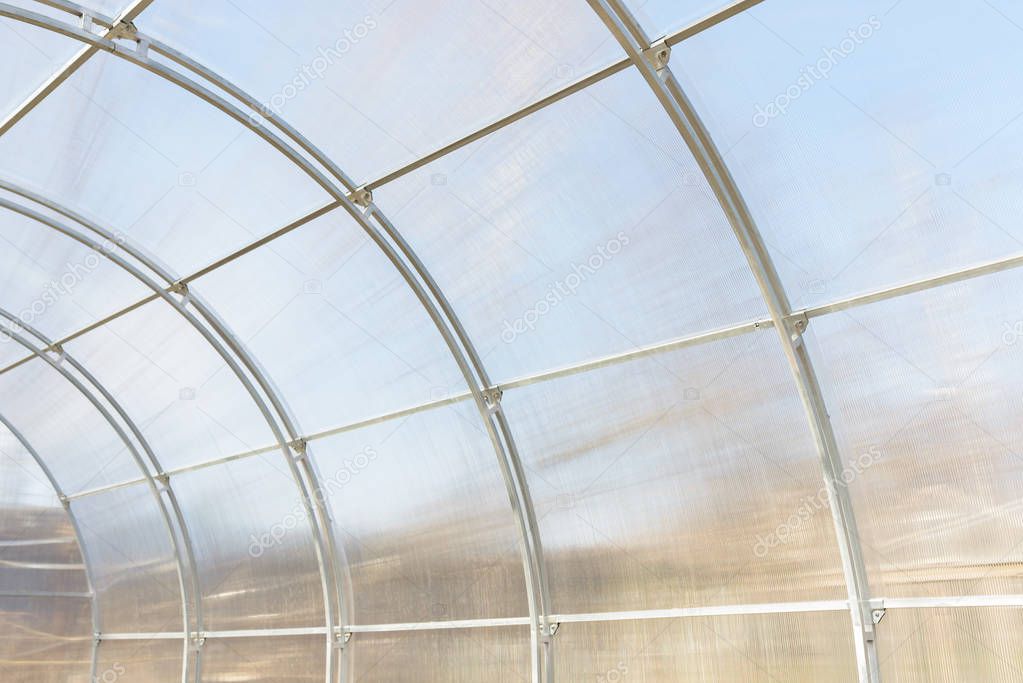 Greenhouse made of polycarbonate and metal carcass. Small hothouse for private use. Metal construction covered with transparent polycarbonate.