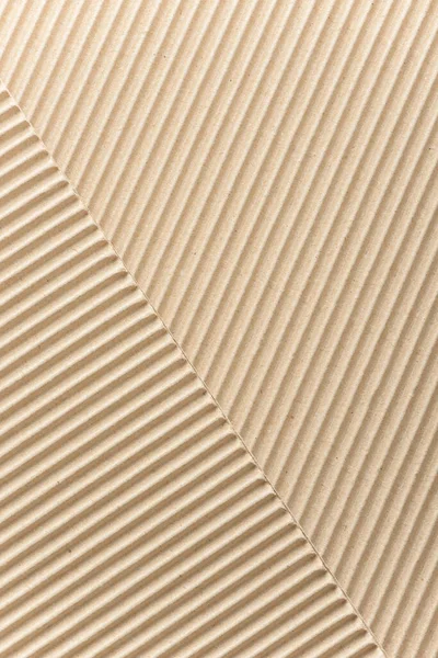 Carton or cardboard packing material. Texture of corrugated paper sheets made from cellulose. Supplies for creating boxes and packaging. Pasteboard background. Natural brown cardboard surface.