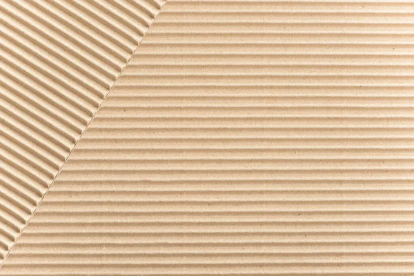 Carton or cardboard packing material. Texture of corrugated paper sheets made from cellulose. Supplies for creating boxes and packaging. Pasteboard background. Natural brown cardboard surface.