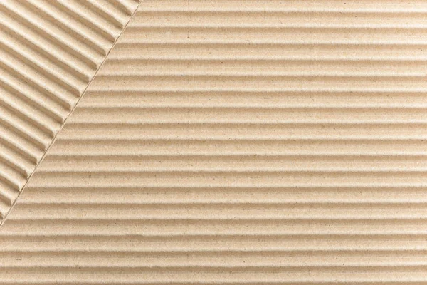 Carton or cardboard packing material. Texture of corrugated paper sheets made from cellulose. Supplies for creating boxes and packaging. Pasteboard background. Natural brown cardboard surface.