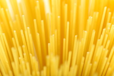 Uzun sarı spagetti makarna malzemesi. Pişmemiş kuru makarna. İnce çiğ erişte. Lezzetli gurme yemekleri için tahıl ürünleri. Yararlı bir karbonhidrat kaynağı. Sağlıklı İtalyan makarnası.