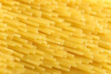 Uzun sarı spagetti makarna malzemesi. Pişmemiş kuru makarna. İnce çiğ erişte. Lezzetli gurme yemekleri için tahıl ürünleri. Yararlı bir karbonhidrat kaynağı. Sağlıklı İtalyan makarnası.