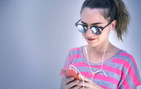Young modern woman heating music with her cellphone — Stock Photo, Image