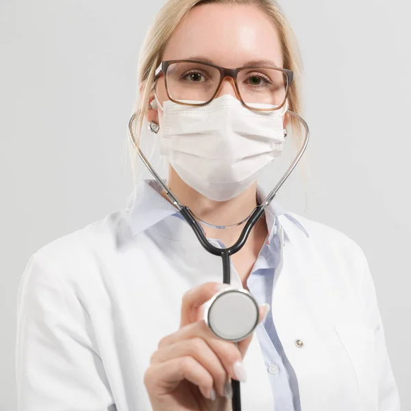 Young female doctor with stethoscope and medical face mask — Stock Photo, Image