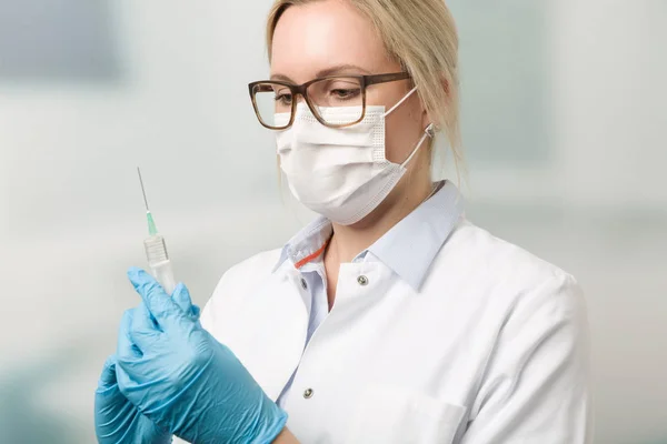 Young female doctor with a syringe with clinic in background — Stock Photo, Image