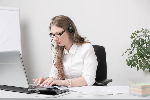 Joven mujer de negocios feliz con auriculares en el escritorio — Foto de Stock