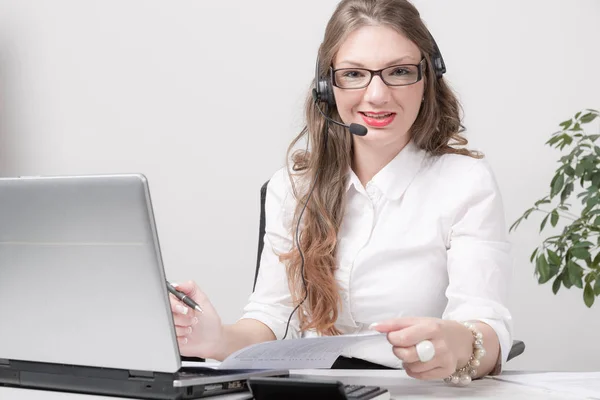 Joven mujer de negocios feliz con auriculares en el escritorio — Foto de Stock