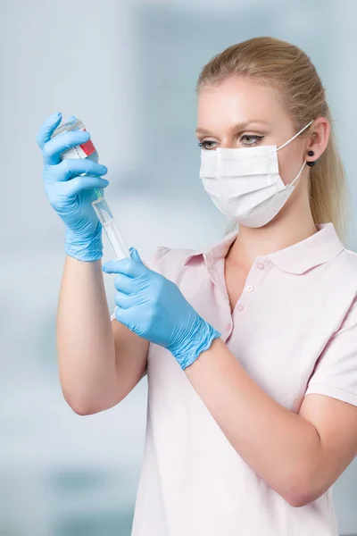 Infermiere tira su una siringa con clinica sullo sfondo — Foto Stock