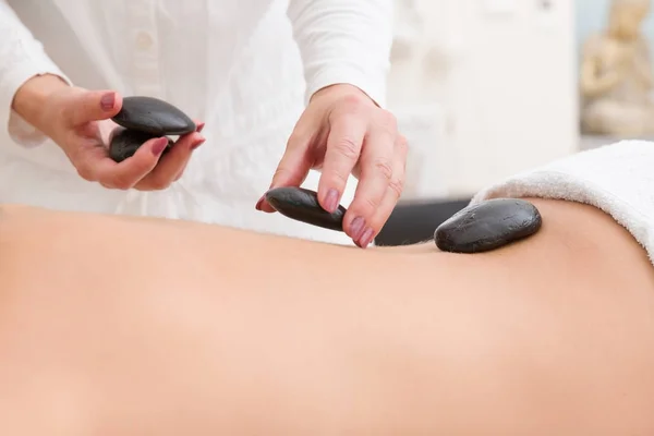 hot stones are put on a womans back for a massage in a spa