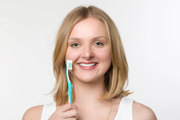 Молодая улыбающаяся женщина показывает зубную щетку — стоковое фото