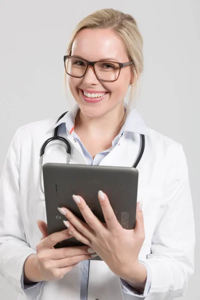 Sonriente joven doctora con estetoscopio y una almohadilla — Foto de Stock