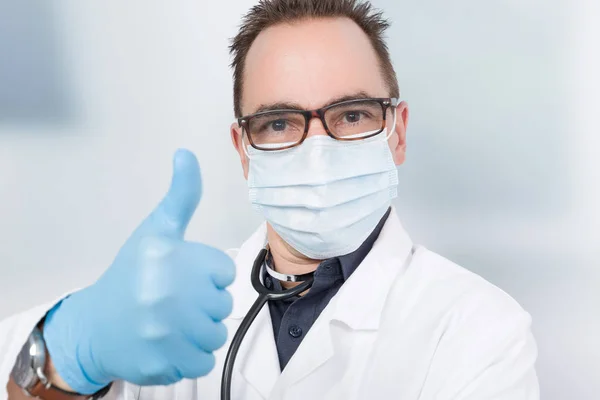 doctor with medical face mask and medical gloves shows thumb up