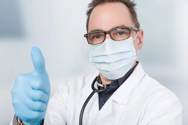 doctor with medical face mask and medical gloves shows thumb up