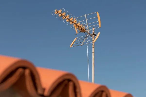 Televizní anténa na střeše před modrou oblohou — Stock fotografie