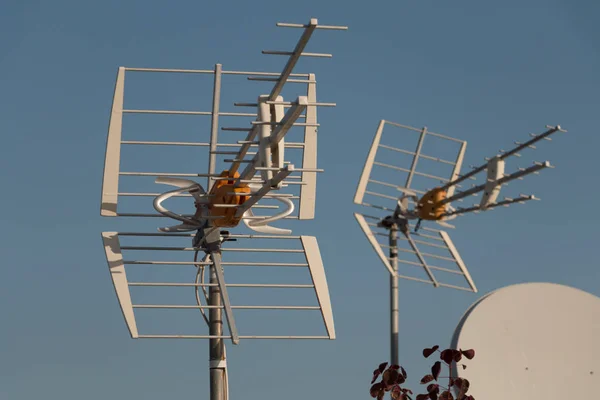 Antenas de televisión en una azotea frente al cielo azul — Foto de Stock