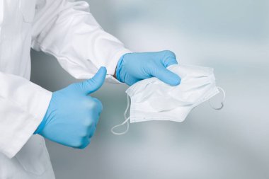 close up of doctor's hand with a medical face mask and thumbs up