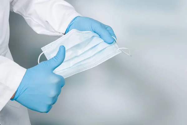 close up of doctor's hand with a medical face mask and thumbs up