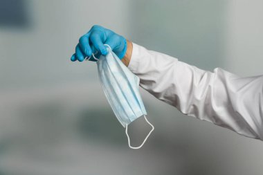 Doktorun elinin tıbbi eldivenlerle kapatılması enfeksiyondan korunmak için tıbbi yüz maskesi gösteriyor.