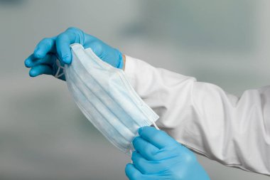 Doktorun elinin tıbbi eldivenlerle kapatılması enfeksiyondan korunmak için tıbbi yüz maskesi gösteriyor.