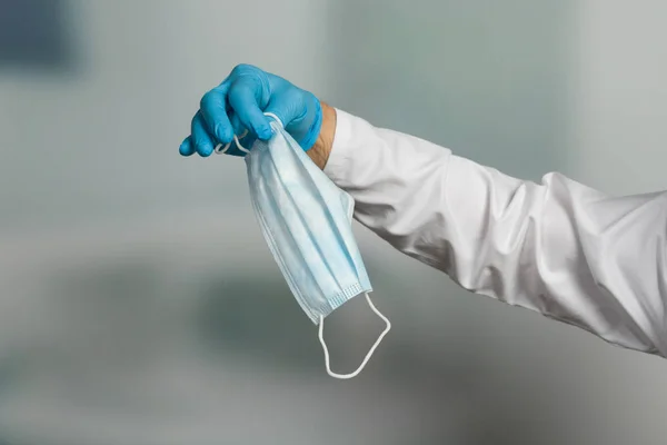Doktorun elinin tıbbi eldivenlerle kapatılması enfeksiyondan korunmak için tıbbi yüz maskesi gösteriyor.