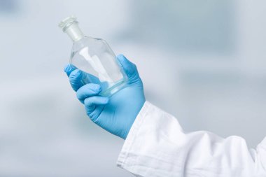 Eldivenli el laboratuvar arının önünde boş bir matara tutuyor. 