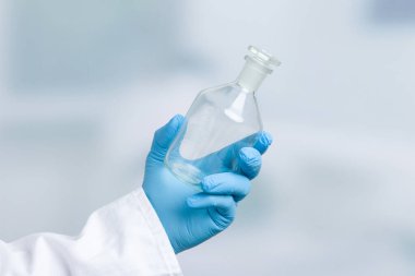 Eldivenli el laboratuvar arının önünde boş bir matara tutuyor. 