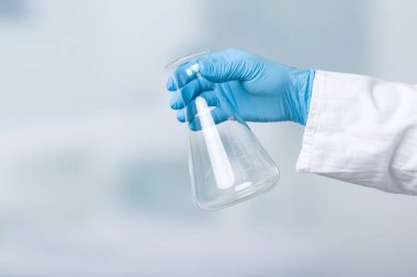 Eldivenli el laboratuvar arının önünde boş bir matara tutuyor.