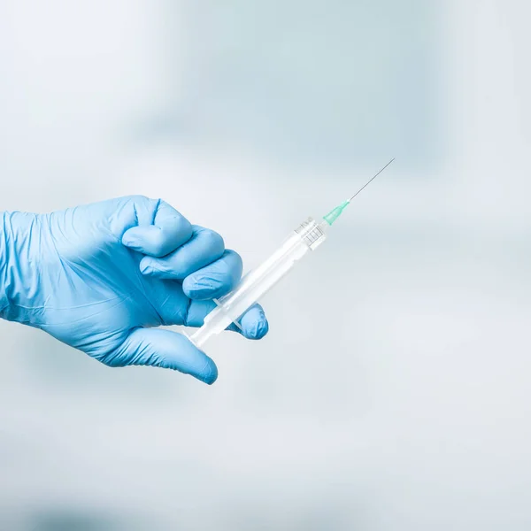 Close up of doctor\'s hand in medical gloves with a syringe